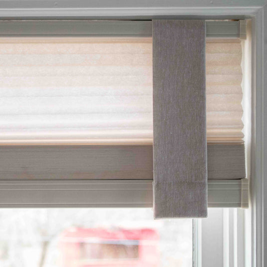 Close-up of a Lift Luxe Shade Strap in Linen Beige securing a pleated window shade. The strap blends seamlessly with the fabric, ensuring a polished, structured look.